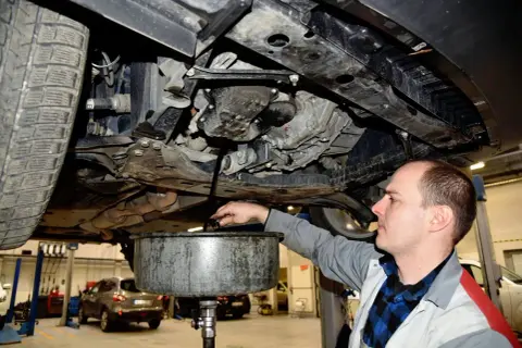 Mechanik spuszcza zużyty olej z silnika. Regularna wymiana oleju co ile kilometrów zapewnia sprawne działanie auta.