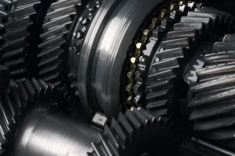 Zbliżenie na metalowe koła zębate, sugerujące awarię skrzyni biegów. Widoczne elementy mechanizmu, gotowe do naprawy.