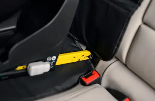 Żółty element mocujący fotelik samochodowy do systemu ISOFIX. Czy baza isofix pasuje do każdego fotelika? Sprawdź mocowanie.