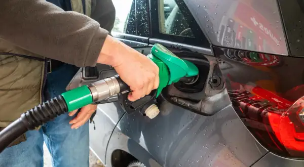 Tankowanie samochodu z silnikiem diesla. Zielona dysza dystrybutora wlewa paliwo do baku.