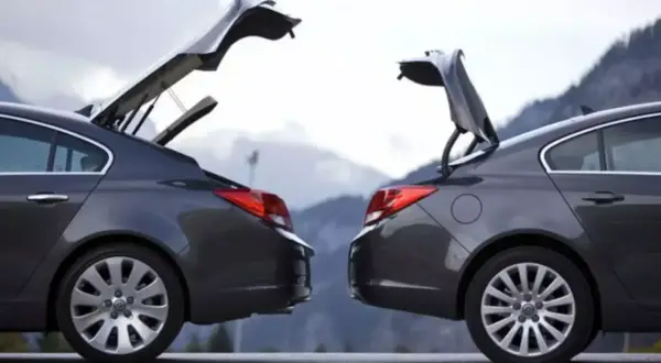 Dwa ciemnoszare sedany z otwartymi bagażnikami, przypominające kształtem hatchback. Góry w tle.