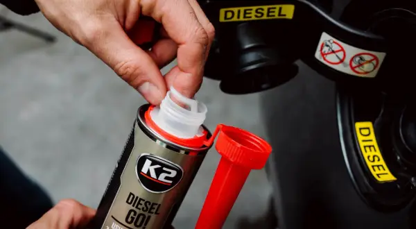 Dłoń otwiera dodatek do paliwa K2 Diesel Go!, który pomaga zapobiegać zamarzaniu diesla. Wskaźnik "DIESEL" na klapce wlewu.