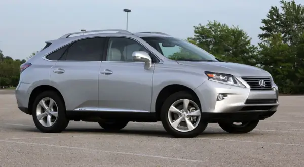 Srebrny Lexus RX 450h, jeden z najmniej awaryjnych SUV-ów 10-letnich, zaparkowany na placu.
