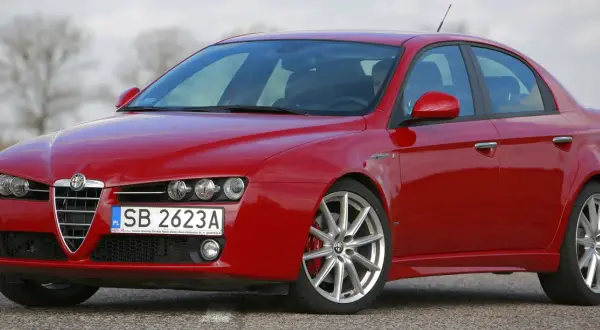 Czerwone Alfa Romeo 159 na drodze. Nawet piękny samochód doświadcza utraty wartości, gdy czas mija.