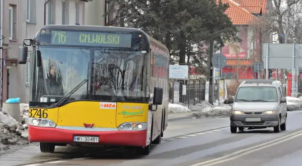 Żółto-czerwony autobus miejski linii 716 jedzie po mokrej drodze. Czy autobus ma pierwszeństwo? Obok jedzie srebrny van.