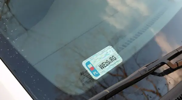 Naklejki na samochód, w tym obowiązkowe naklejki z numerem rejestracyjnym, umieszczone na przedniej szybie.