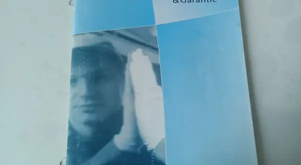 Karta serwisowa pojazdu Toyota z napisem "Kundendienst & Garantie". Widoczny fragment twarzy mechanika w białej rękawiczce.