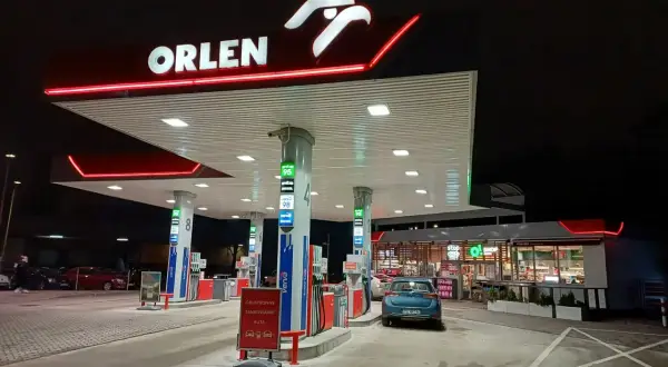 Nocna stacja Orlen z podświetlanym logo. Samochód czeka na tankowanie, bo kiedy tańsze paliwo, warto zatankować.