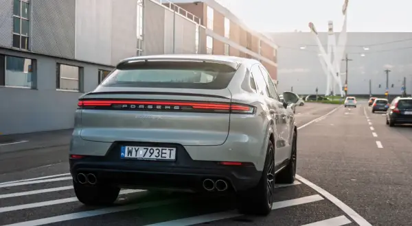 Szare Porsche Cayenne S z polskimi tablicami rejestracyjnymi na drodze. Porsche to niemiecka marka samochodów sportowych.