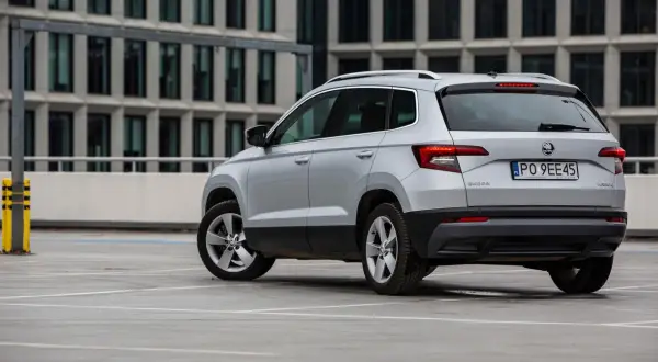 Srebrny Skoda Karoq, jeden z najmniej awaryjnych aut segmentu B, parkuje przed nowoczesnym budynkiem.