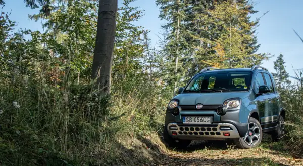 Szary Fiat Panda Cross 4x4 na leśnej ścieżce, gotowy na przygodę.