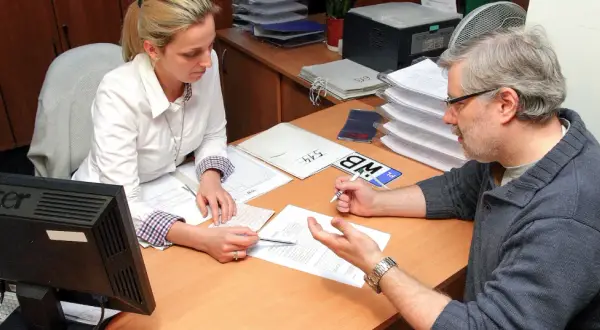 Mężczyzna z okularami i kobieta przy biurku analizują dokumenty, szukając rozwiązania problemu: błąd w CEPIK jak skorygować.