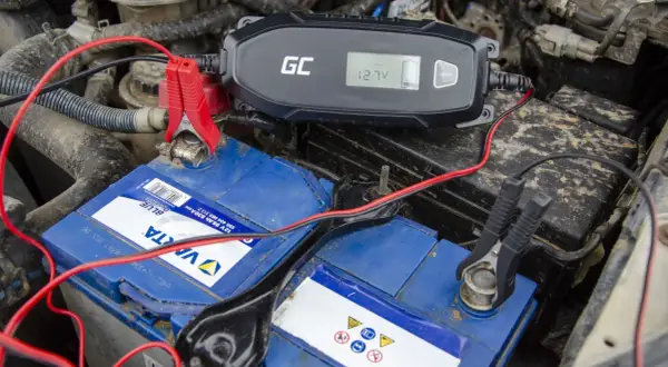 Ładowarka GC podłączona do akumulatora samochodowego. Wyświetlacz pokazuje 12.7V, co oznacza, że akumulator ładuje się na postoju.