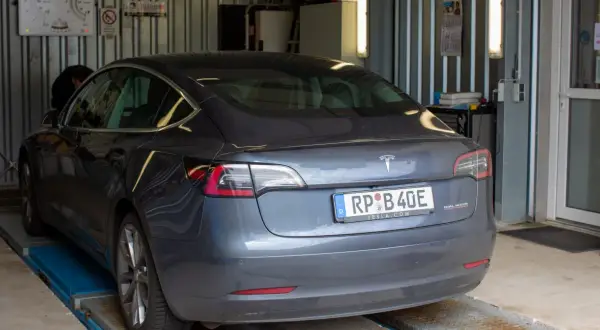 Szary Tesla na podnośniku, mechanik sprawdza, jak dbać o samochód.