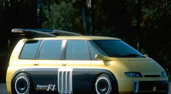 Żółto-szary Renault Espace F1 z masywnym spojlerem i sportowymi felgami, gotowy do wyścigu.