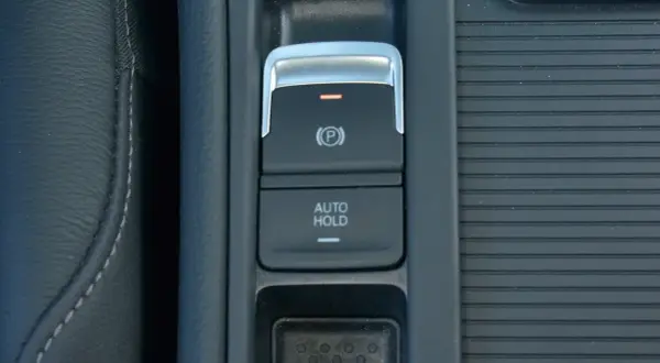 Przycisk AUTO HOLD w samochodzie. To funkcja, która automatycznie utrzymuje pojazd w miejscu po zatrzymaniu.