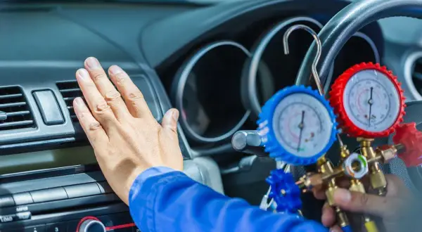 Ręka sprawdza nawiew, gdy mechanik podłącza manometry do układu. Klimatyzacja nie chłodzi, więc czas na diagnozę.