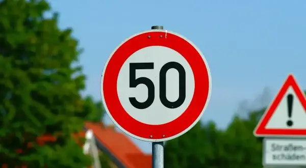 Znak ograniczenia prędkości do 50 km/h. Jaka prędkość w terenie zabudowanym jest dozwolona? Ten znak informuje kierowców.