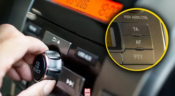 Dłoń kręci pokrętłem głośności w radiu samochodowym. Widać przycisk AF, który pozwala na automatyczne przełączanie częstotliwości.