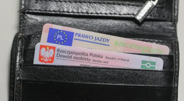 Czarny portfel z polskim dowodem osobistym i prawem jazdy. Na dokumencie prawa jazdy widnieje napis "PRAWO JAZDY" oraz symbol PL.