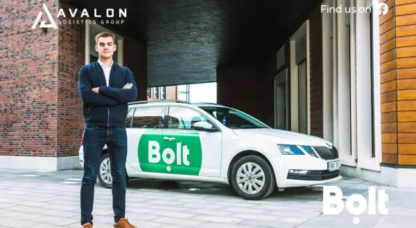 Młody mężczyzna stoi obok białego samochodu z logo Bolt. Zastanawiasz się, ile można zarobić na Bolcie?