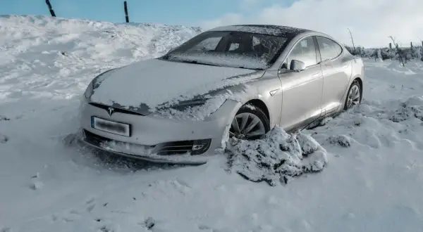 Srebrny Tesla utknął w zaspie śnieżnej. Czy to ogranicza zasięg samochodu elektrycznego w zimowych warunkach?