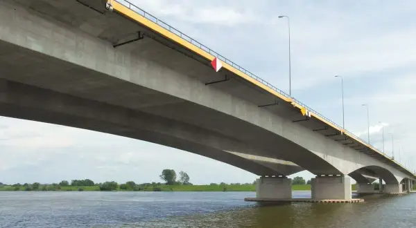 Betonowy most, najdłuższy w Polsce, rozciąga się nad szeroką rzeką, łącząc brzegi w słoneczny dzień.