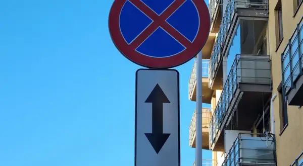Znak zakazu zatrzymywania ze strzałką w górę i w dół, wskazującą na zakaz postoju w obu kierunkach.