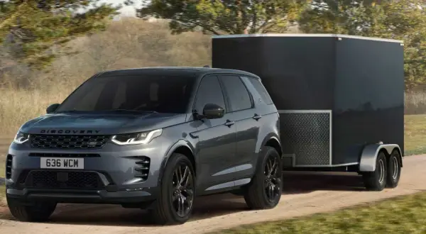 Szare Discovery Sport z przyczepą kempingową na drodze. Idealne auto do przyczepy kempingowej, gotowe na przygodę.