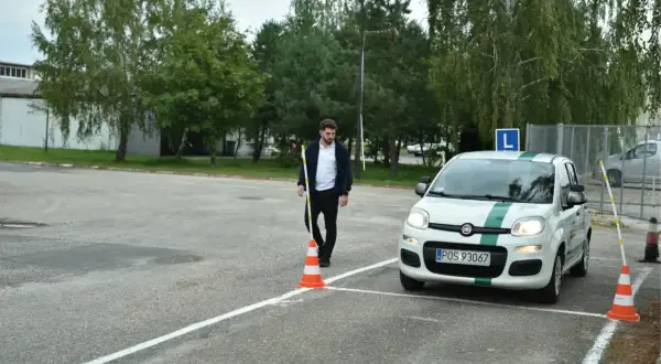 Egzaminator ustawia pachołek, a kursant wykonuje hamowanie awaryjne na placu manewrowym.