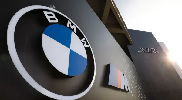 Logo BMW i oznaczenie M, symbole niemieckich marek samochodów, na ciemnej ścianie budynku.