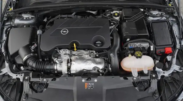 Silnik samochodu Opel z logo marki. Pod maską widać turbosprężarkę i zbiornik płynu chłodniczego. To silnik CDTI, co to znaczy? To silnik Diesla z turbodoładowaniem.