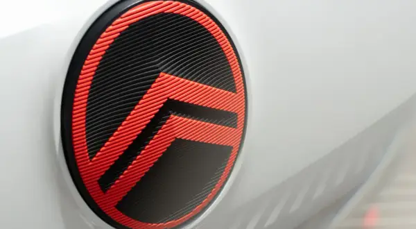 Nowe logo Citroëna w kolorze czarno-czerwonym, z charakterystycznymi jodełkami, zdobi białą karoserię samochodu.