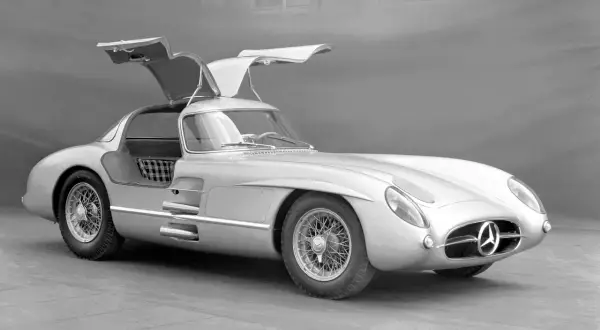 Srebrny Mercedes-Benz 300 SLR z otwieranymi do góry drzwiami, uznawany za najdroższe auto na świecie, prezentuje swoją legendarną sylwetkę.