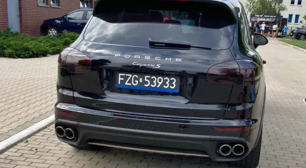 Czarne tablice rejestracyjne wykazują Porsche Cayenne S.