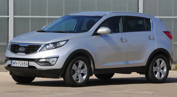 Srebrny Kia Sportage, jeden z najmniej awaryjnych aut terenowych, zaparkowany przed budynkiem.