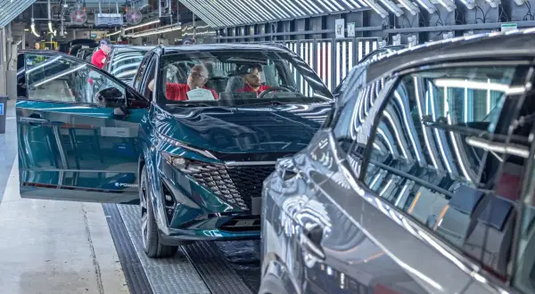 Nowy Nissan powstaje w fabryce. Pracownicy kontrolują jakość pojazdu, który opuszcza linię produkcyjną.