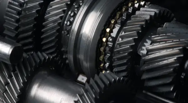 Zbliżenie na metalowe koła zębate, sugerujące awarię skrzyni biegów. Widoczne elementy mechanizmu, gotowe do naprawy.