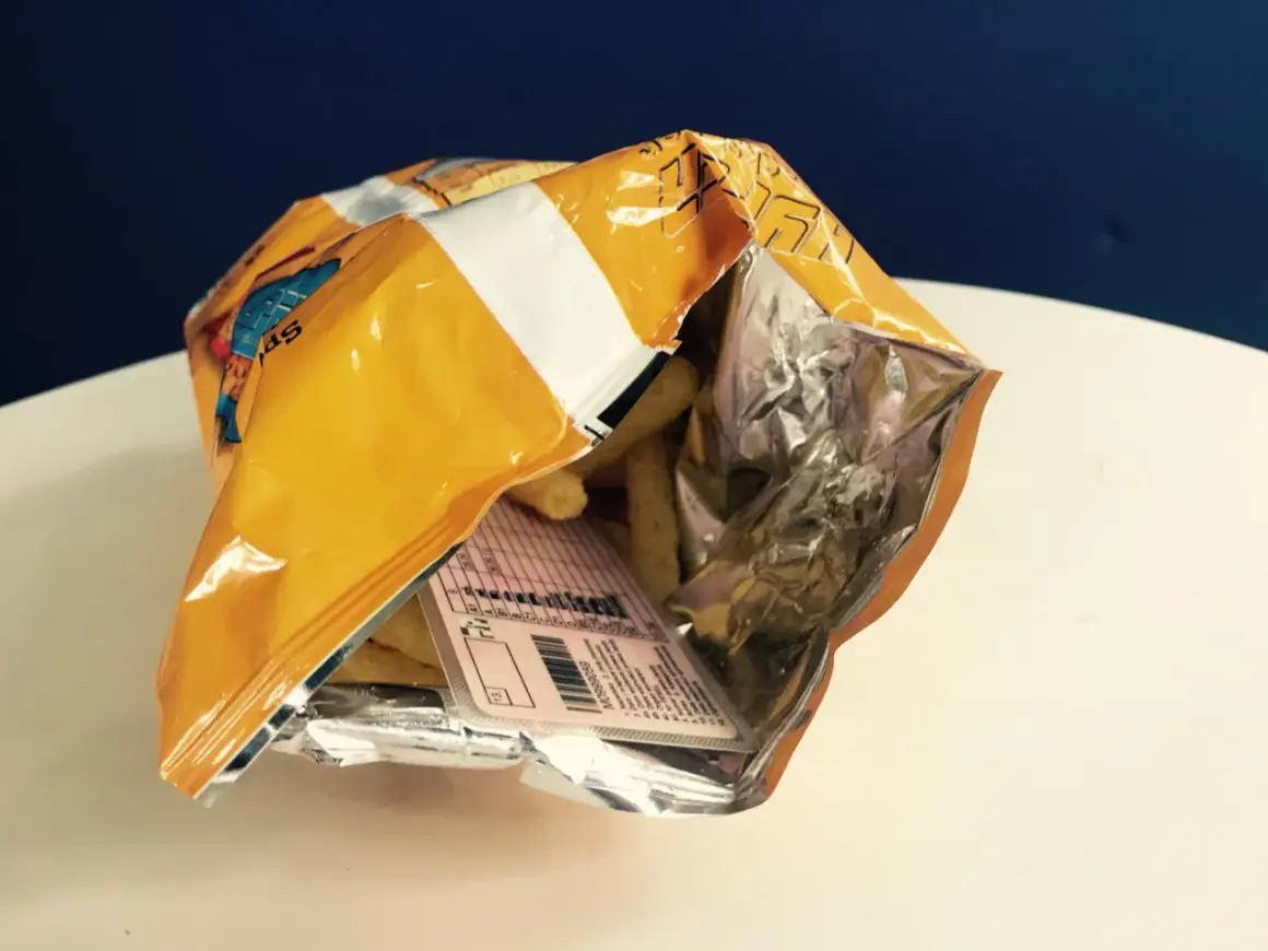 Otwarta paczka chipsów, a w środku etykieta z danymi, jakby to było **prawo jazdy w chipsach**.