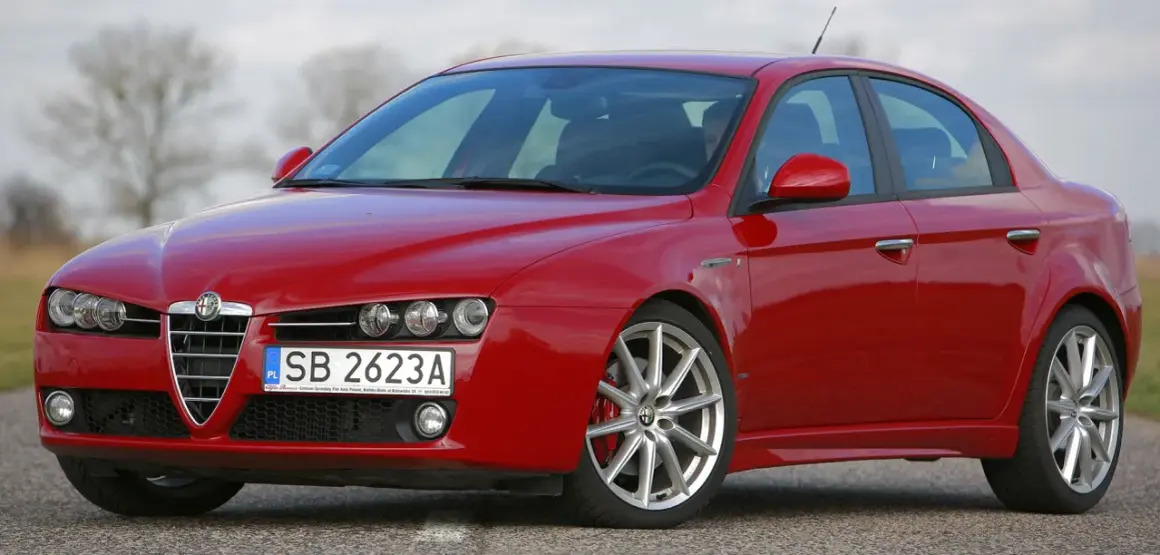 Czerwone Alfa Romeo 159 na drodze. Nawet piękny samochód doświadcza utraty wartości, gdy czas mija.
