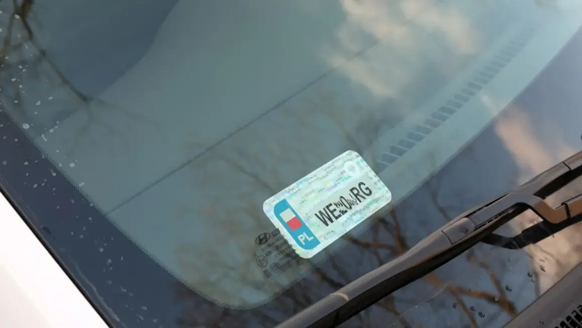 Naklejki na samochód, w tym obowiązkowe naklejki z numerem rejestracyjnym, umieszczone na przedniej szybie.