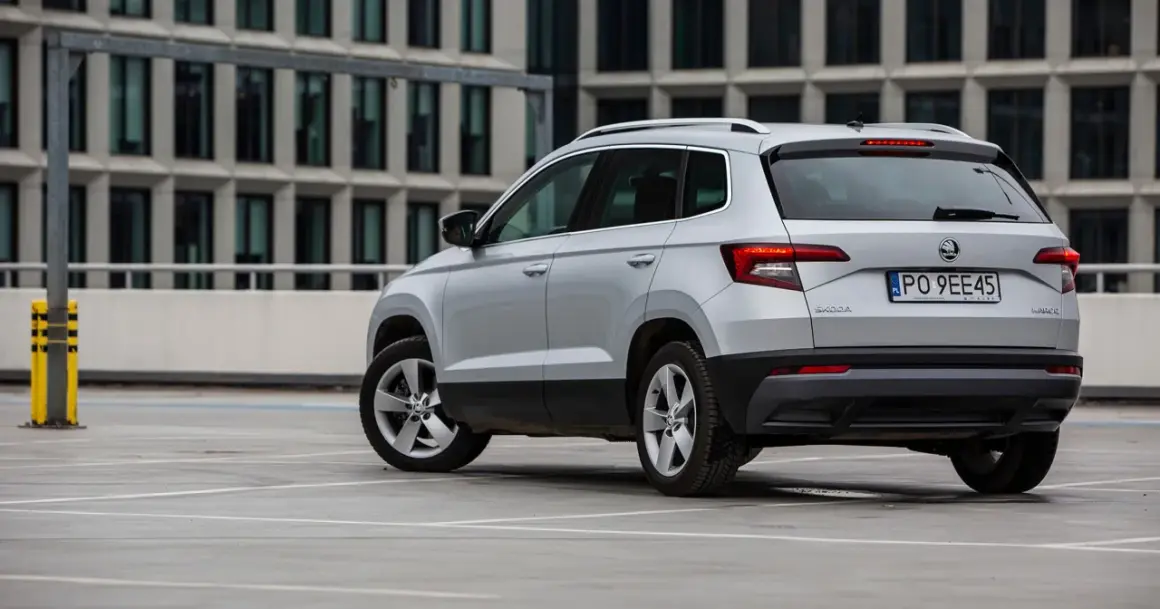 Srebrny Skoda Karoq, jeden z najmniej awaryjnych aut segmentu B, parkuje przed nowoczesnym budynkiem.