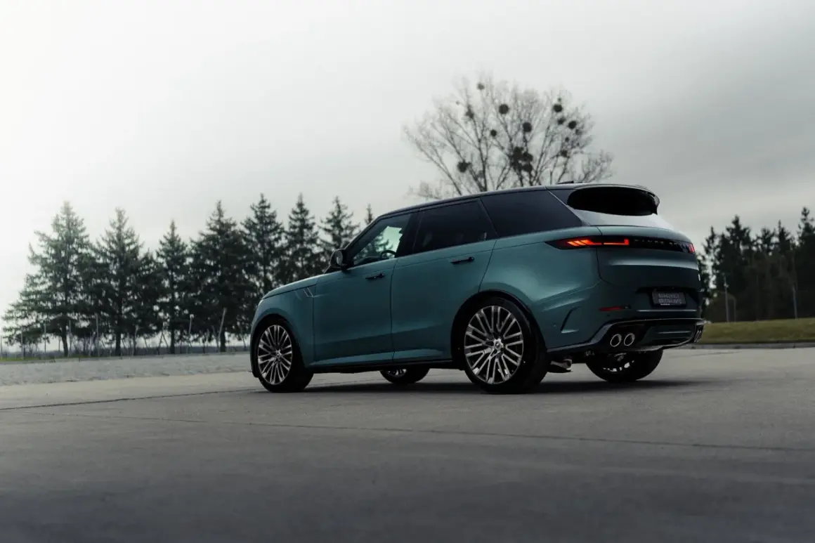 Elegancki, zielony Range Rover, jeden z prestiżowych angielskich marek samochodów, parkuje na tle drzew.