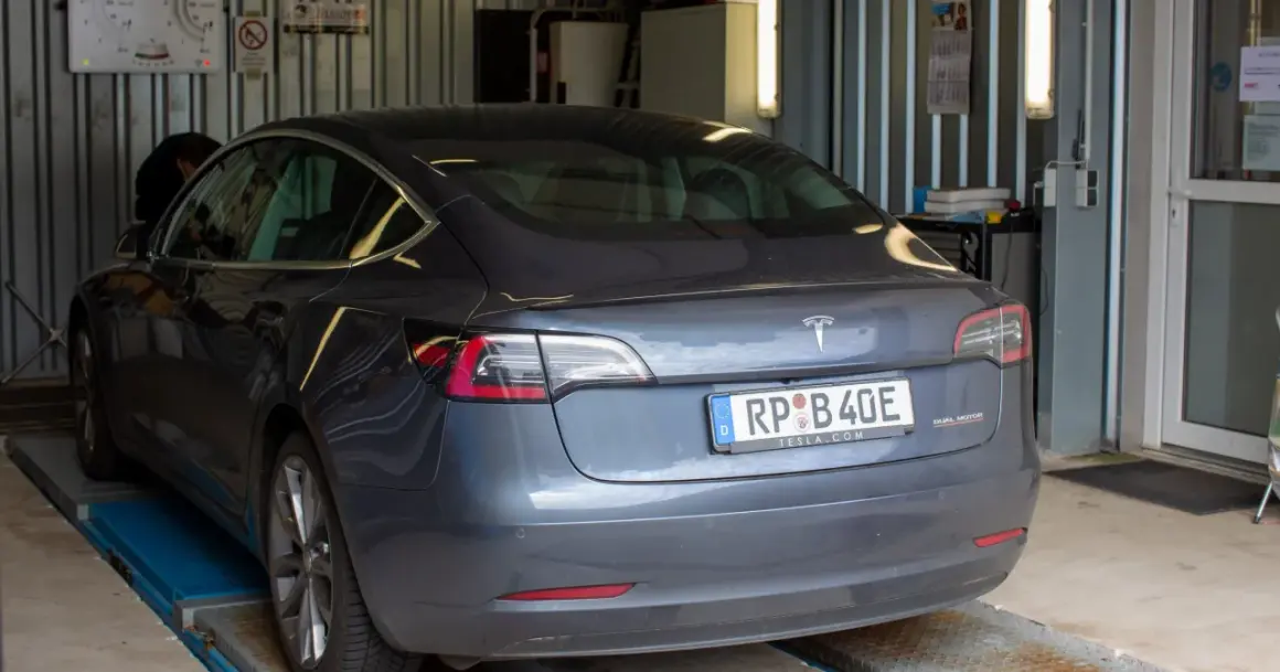 Szary Tesla na podnośniku, mechanik sprawdza, jak dbać o samochód.