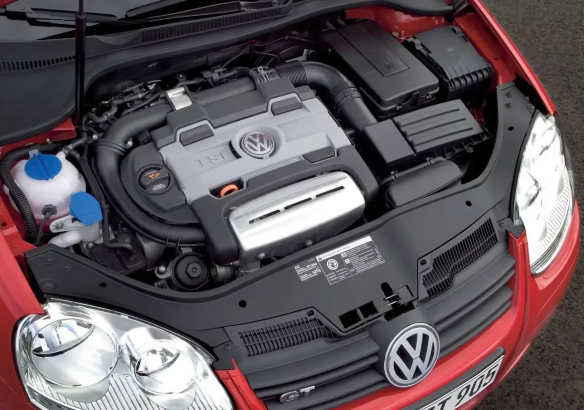 Silnik 1.4 TSI Twincharger w czerwonym Volkswagenie. Widoczny jest blok silnika z logo VW, przewody i elementy układu dolotowego.
