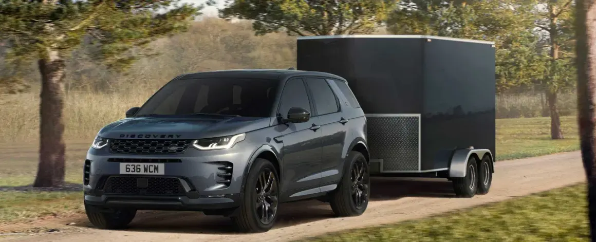 Szare Discovery Sport z przyczepą kempingową na drodze. Idealne auto do przyczepy kempingowej, gotowe na przygodę.
