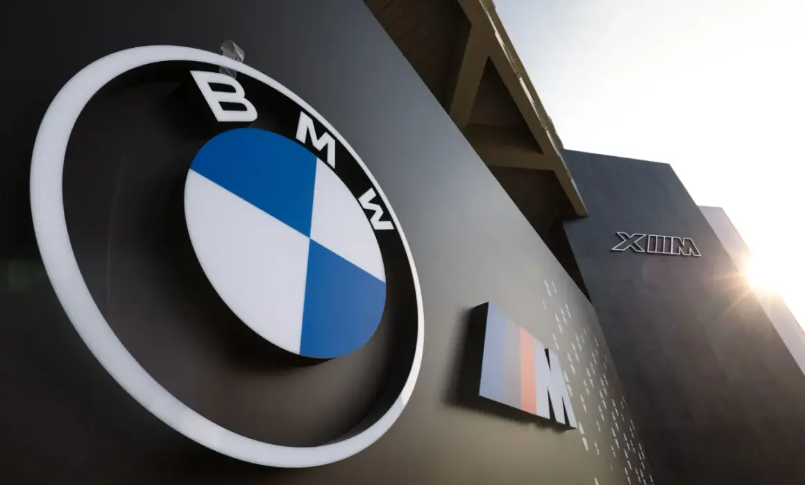 Logo BMW i oznaczenie M, symbole niemieckich marek samochodów, na ciemnej ścianie budynku.