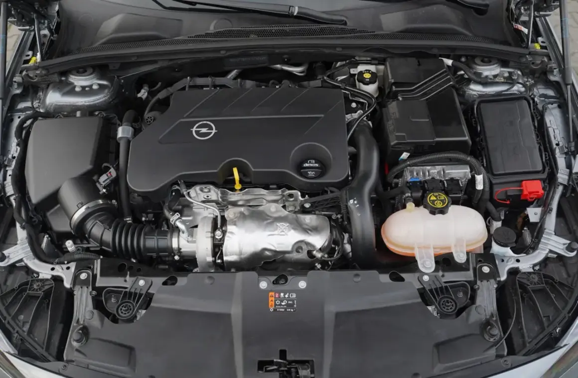 Silnik samochodu Opel z logo marki. Pod maską widać turbosprężarkę i zbiornik płynu chłodniczego. To silnik CDTI, co to znaczy? To silnik Diesla z turbodoładowaniem.