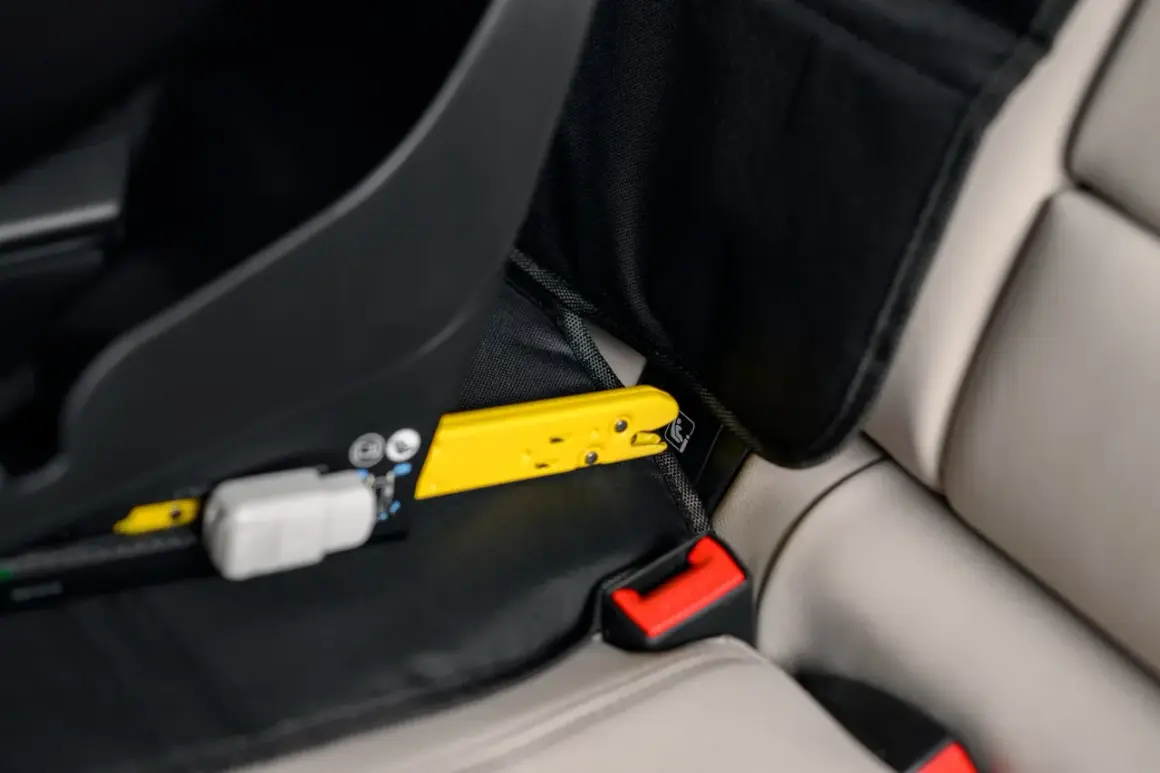 Żółty element mocujący fotelik samochodowy do systemu ISOFIX. Czy baza isofix pasuje do każdego fotelika? Sprawdź mocowanie.