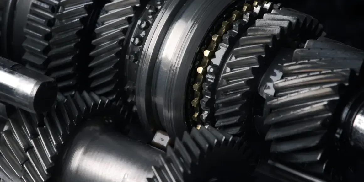 Zbliżenie na metalowe koła zębate, sugerujące awarię skrzyni biegów. Widoczne elementy mechanizmu, gotowe do naprawy.